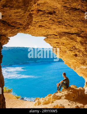 Île de Gozo Malte, jeune homme et une vue de la baie de Ramla, de l'intérieur de la grotte de Tal Mixta Gozo Banque D'Images