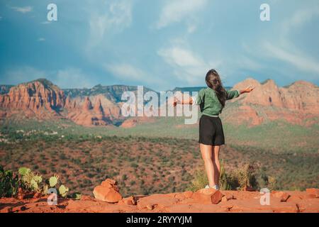 Jeune femme randonneuse au bord d'une falaise à Cathedral Rock à Sedona, Arizona. Vue depuis Scenic Cathedral Rock à Sedona avec bl Banque D'Images