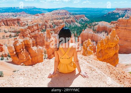 Femme randonneuse à Bryce Canyon se reposant profitant de la vue dans un magnifique paysage naturel avec des hoodoos, des pinacles et des flèches rocheuses formatio Banque D'Images