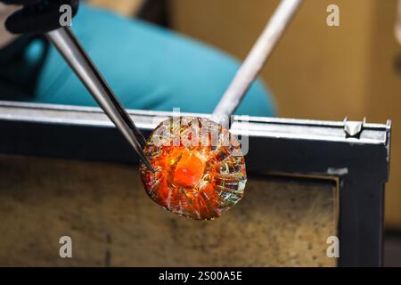 Travaux d'un atelier de soufflage de verre en cours. Verre fondu en forme de fleur Banque D'Images