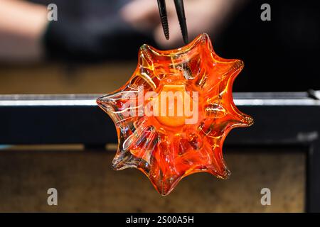 Verre fondu chaud rouge en forme de fleur, fonctionne à l'atelier de soufflage de verre Banque D'Images