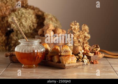 Baklava avec noix et miel sur fond beige. Désert oriental traditionnel dans un plat en bois. Copier l'espace. Banque D'Images