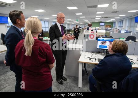 Le premier ministre John Swinney accompagné de Valerie Guilford, gestionnaire d’appels, en tant que Patrick Rafferty, directeur adjoint des soins infirmiers NHS24, et Julie Lindsay, gestionnaire des services cliniques NHS24, regardent, lors de sa visite au centre d’appels NHS 24 à Dundee, où il a rencontré le personnel et visité les installations avant la période des fêtes. Date de la photo : lundi 23 décembre 2024. Banque D'Images