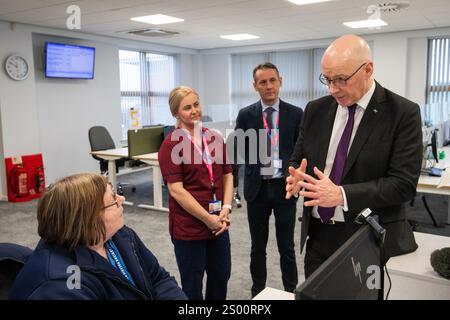 Le premier ministre John Swinney accompagné de Valerie Guilford, gestionnaire d’appels, en tant que Patrick Rafferty, directeur adjoint des soins infirmiers NHS24, et Julie Lindsay, gestionnaire des services cliniques NHS24, regardent, lors de sa visite au centre d’appels NHS 24 à Dundee, où il a rencontré le personnel et visité les installations avant la période des fêtes. Date de la photo : lundi 23 décembre 2024. Banque D'Images