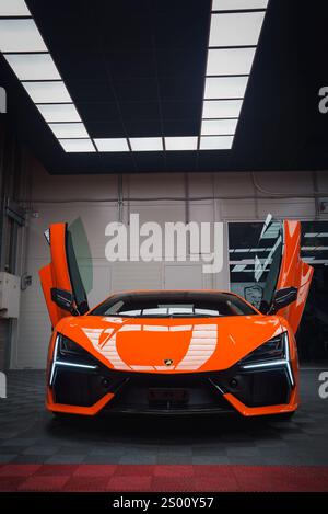 Orange Lamborghini Revuelto avec portes ciseaux ouvertes à l'intérieur Banque D'Images