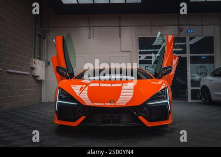 Orange Lamborghini Revuelto avec portes en ciseaux dans la salle d'exposition moderne Banque D'Images