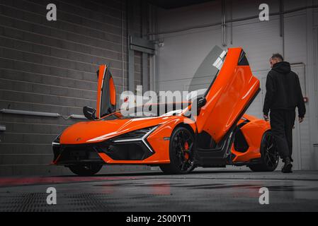 Orange Lamborghini Revuelto avec portes ciseaux dans garage industriel Banque D'Images