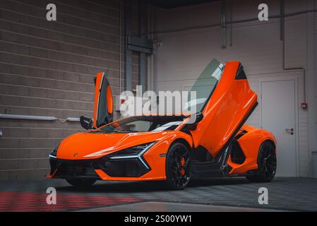 Orange Lamborghini Revuelto avec portes ciseaux ouvertes à l'intérieur Banque D'Images