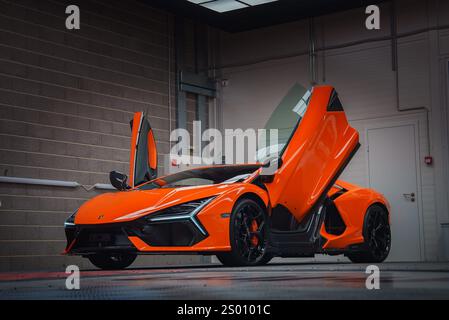 Orange Lamborghini Revuelto avec portes en ciseaux ouvertes dans la salle d'exposition Banque D'Images