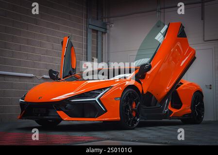 Orange Lamborghini Revuelto avec portes ciseaux ouvertes à l'intérieur Banque D'Images