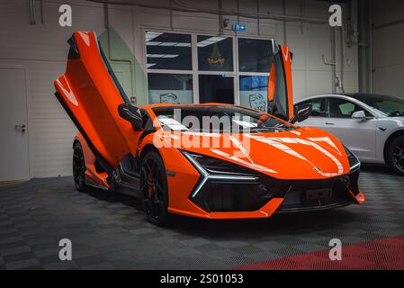 Orange Lamborghini Revuelto avec portes ciseaux ouvertes à l'intérieur Banque D'Images