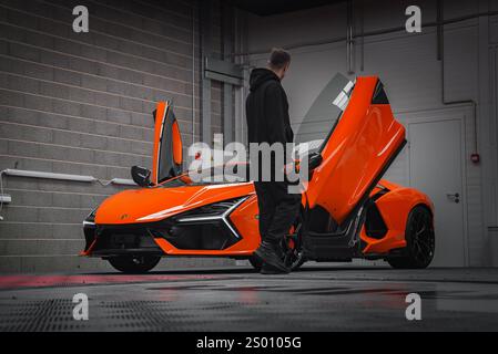 Orange Lamborghini Revuelto avec portes en ciseaux ouvertes dans la salle d'exposition Banque D'Images