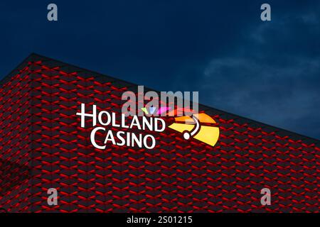 Utrecht, pays-Bas. 25 septembre 2024. Logo coloré Holland Casino illuminé la nuit sur le bâtiment éclairé en rouge. avec de lourds nuages dans le dos Banque D'Images