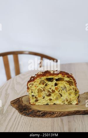 Gros plan de panettone tranché sur un dessous de verre en bois d'olivier, placé sur une table en bois clair. La prise de vue se concentre sur la texture douce et aérée avec beaucoup de petits Banque D'Images