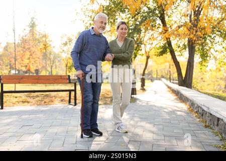 Soignant aidant l'homme âgé dans le parc. Service de soins à domicile Banque D'Images