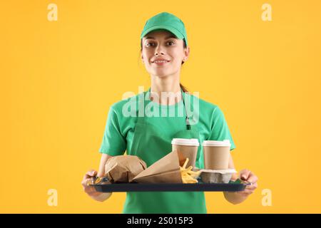 Travailleur de la restauration rapide tenant le plateau avec commande sur fond orange Banque D'Images