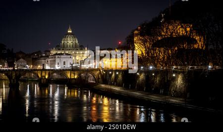 Une vue imprenable de nuit sur la Cité du Vatican, avec la basilique Pierre illuminée contre le ciel nocturne. Le Tibre reflète les lumières de th Banque D'Images