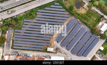 La perspective aérienne présente une grande installation de panneaux solaires située à côté d'une autoroute très fréquentée. Les panneaux sont soigneusement disposés en rangées, entourés de gr Banque D'Images