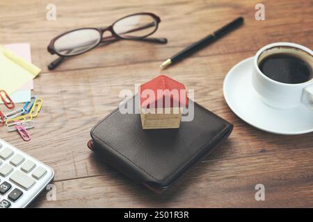 porte-monnaie en cuir avec clé, modèle de maison, calculatrice et café sur la table en bois Banque D'Images