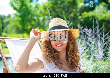 fröhliche Junge Frau mit Sonnenbrille und Strohhut *** jeune femme joyeuse avec lunettes de soleil et chapeau de paille Banque D'Images