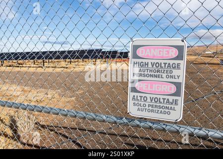 La signalisation à l'extérieur d'une grande ferme solaire dans le désert du nord-ouest du nevada avertit du danger de haute tension en anglais et en espagnol Banque D'Images
