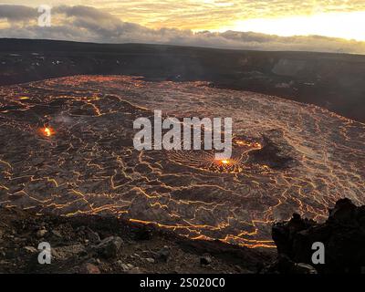 Kilauea (États-Unis d'Amérique). 23 décembre 2024. Kilauea (États-Unis d'Amérique). 23 décembre 2024. Un lac de lave active brille dans la caldeira sommitale du volcan Kilauea alors que le soleil se lève au parc national des volcans d'Hawaï, le 23 décembre 2024 près de Hilo, Hawaï. Une éruption fraîche a commencé à 2h20 heure locale au cratère Halemaumau tirant un esclave à 262 pieds dans les airs. Crédit : Natalia Deligne/USGS/Alamy Live News Banque D'Images