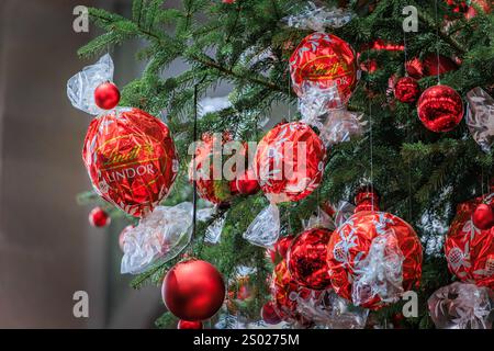 Zurich, Suisse - 24 novembre 2024 : arbre de Noël emblématique Lindt à Zurich SBB Hauptbahnhof orné d'ornements rouges et de décorations en chocolat Banque D'Images