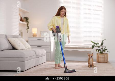 Tapis de nettoyage pour adolescente avec aspirateur sans fil et son chien chihuahua mignon assis sur le sol à la maison Banque D'Images