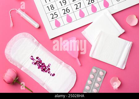 Composition de pose plate avec calendrier et produits menstruels sur fond rose Banque D'Images