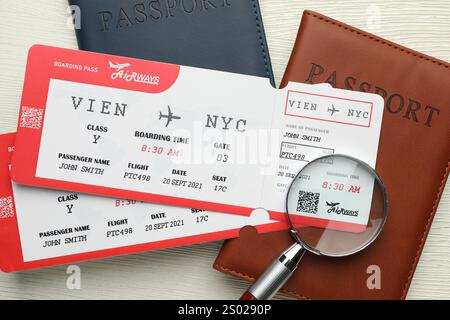 Agence de voyages. Billets d'avion, passeports et loupe sur table en bois clair, pose à plat Banque D'Images