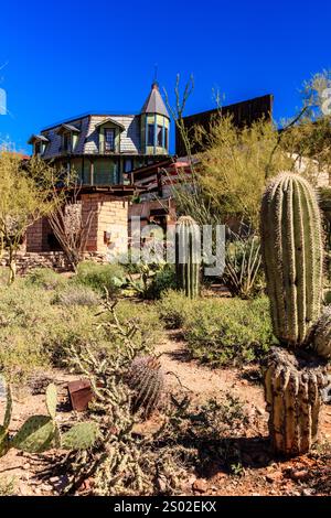 Un paysage désertique avec une grande maison en arrière-plan. La maison est entourée de cactus et d'autres plantes du désert. La scène a un cadre paisible et serein Banque D'Images