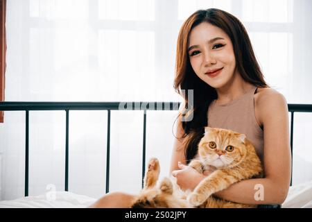 Une femme joyeuse et son chaton Scottish Fold enjoué trouvent le bonheur en compagnie de l'autre Banque D'Images