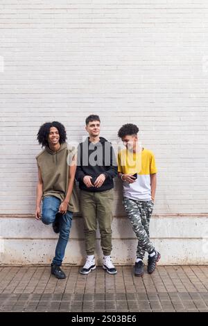 trois amis adolescents appuyés contre un mur blanc Banque D'Images