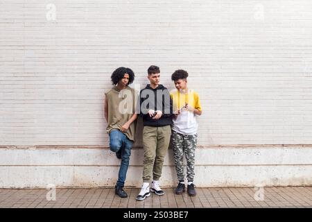 trois amis adolescents appuyés contre un mur blanc Banque D'Images