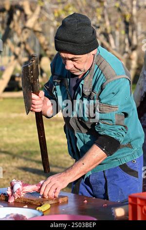 Ohrady, Dunajská Streda, Slovaquie - novembre 30 2024 : abattage de porcs de village traditionnel (zabíjačka), homme hachant la viande avec une hache Banque D'Images