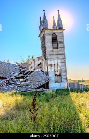Une église avec un toit cassé et une grande arche. L'église est vieille et abandonnée. Le soleil brille sur l'église, la faisant paraître encore plus désolée Banque D'Images