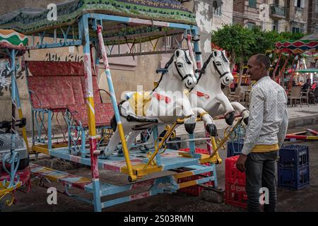 Un carrousel coloré et vintage pour enfants dans les rues d'Alexandrie, en Égypte, avec des motifs de foire vibrants et des figures fantaisistes. Banque D'Images