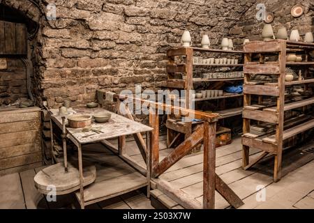 Une pièce avec une table et des étagères pleines de poterie. La chambre a une atmosphère rustique et à l'ancienne Banque D'Images