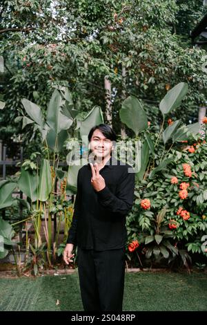 Un homme d'Asie du Sud-est faisant un signe de paix avec ses doigts, exprimant une ambiance joyeuse et détendue Banque D'Images