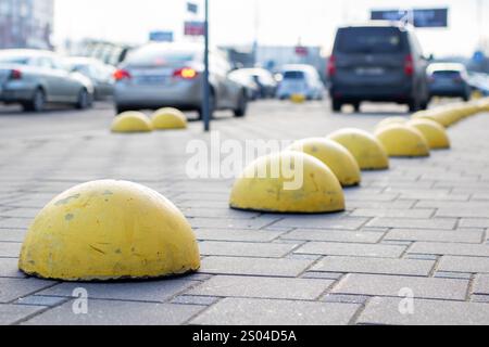 Une rangée distincte de bosses texturées jaune vif est visible sur un trottoir de briques, tandis que diverses voitures peuvent être vues dans le fond lointain Banque D'Images