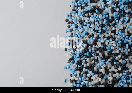 Pile de granulés de plastique colorés sur fond gris, vue de dessus. Espace pour le texte Banque D'Images