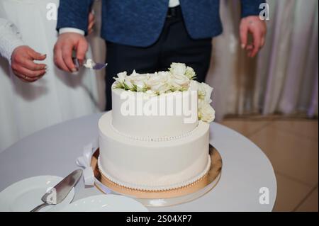 Elégant gâteau de mariage à deux étages décoré de roses et de perles fraîches. Banque D'Images