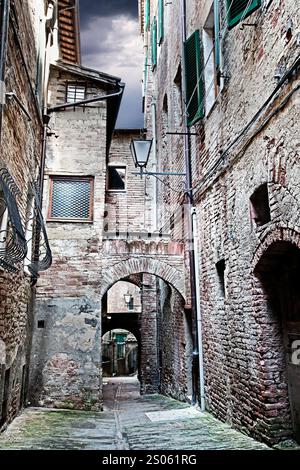 Rue étroite entre les bâtiments avec le ciel dramatique. (Siena. Toscane, Italie) Banque D'Images