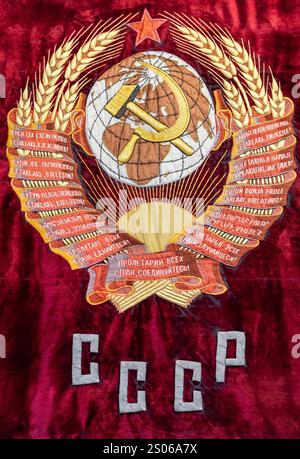Partie centrale du drapeau rouge vintage de l'Union soviétique avec armoiries brodées et texte URSS en russe Banque D'Images