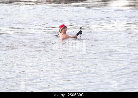 Berlin, Allemagne. 25 décembre 2024. Une femme de l'association 'Berliner Seehunde' baigne dans l'Orankesee pendant la baignade de Noël. Depuis plus de trente ans, les phoques de Berlin viennent à l'Orankesee pour se baigner tous les dimanches d'octobre à avril - les moments forts sont les bains de Noël et le carnaval des bains de glace. Crédit : Paul Zinken/dpa/Alamy Live News Banque D'Images