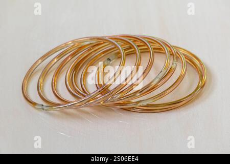 Bracelets en verre doré, affichés sur un fond de tuiles en bois. Les churi ou bracelets sont des accessoires de beauté traditionnels portés par les femmes asiatiques. Banque D'Images