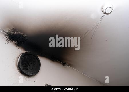 Lampe LED grillée. Une lampe d'abat-jour sur le mur après un incendie. Combustion spontanée et incendie dans un immeuble résidentiel. Détecteur d'alarme incendie intérieur Banque D'Images