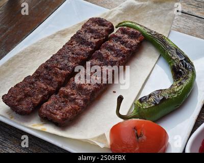 Le plat turc Adana kebab utilise de l'agneau haché assaisonné et grillé avec des épices, servi avec du pain pita, des tomates rôties et des piments verts rôtis Banque D'Images