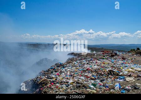 Une montagne de déchets est sur le bord d'une route. Les ordures sont empilées haut et le ciel est bleu Banque D'Images