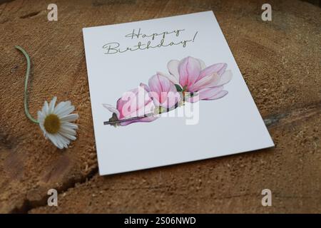 Carte de voeux joyeux anniversaire avec une branche de magnolia peinte à l'aquarelle, carte comme photo de produit en vente sur Etsy, décorée sur une tranche d'arbre, une Marguerite Banque D'Images